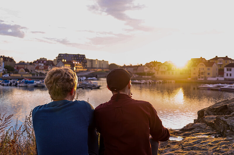 Två personer vid vatten i solnedgång