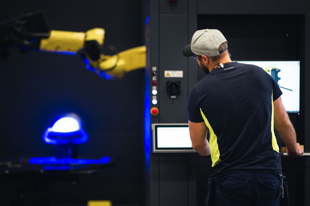 Person arbetar vid robotcell i industrimiljö