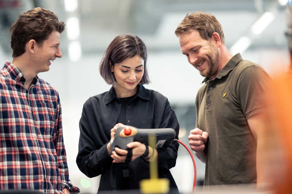 Tre personer diskuterar arbete i industrimiljö
