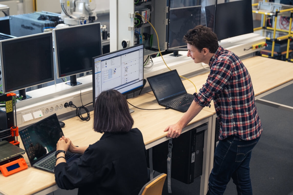 Två personer arbetar vid datorer i teknisk testmiljö