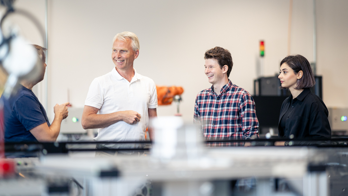 Tre personer i samtal i industrimiljö