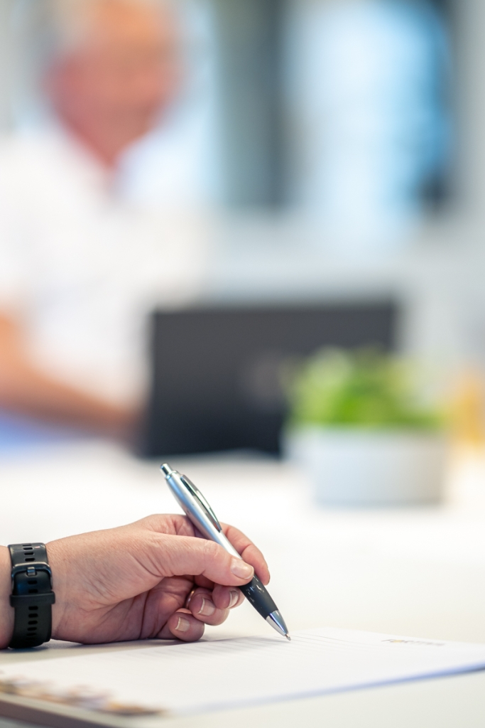 Hand som håller en penna och skriver en ansökan