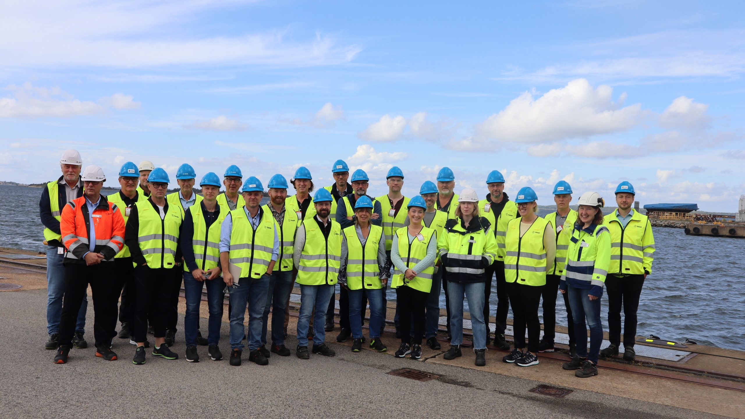 Grupp i varselkläder samlad vid industriområde