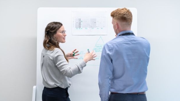 Två personer diskuterar vid whiteboard