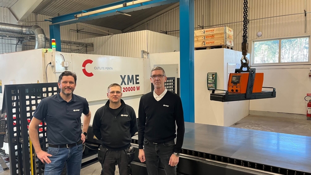Medarbetare på Norje Smidesfabrik framför en fiberlaser.